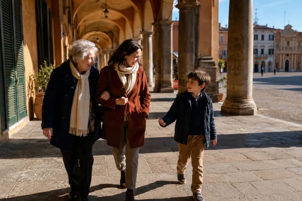 Nonna, figlia e nipote camminano sotto i portici di una città italiana, ridendo, in un pomeriggio soleggiato di fine novembre